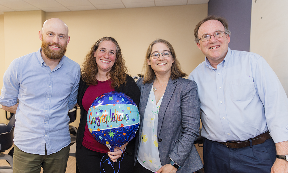 Alison Castellano, the 2024 recipient of the WNE Teaching Excellence Award, stands proudly with previous Teaching Excellence Awardees who eagerly pass her the torch of honor! (L to R) Mike Rust (2022), Alison Castellano (2024), Hillary Bucs (2021), and Tim Vercellotti (2023).