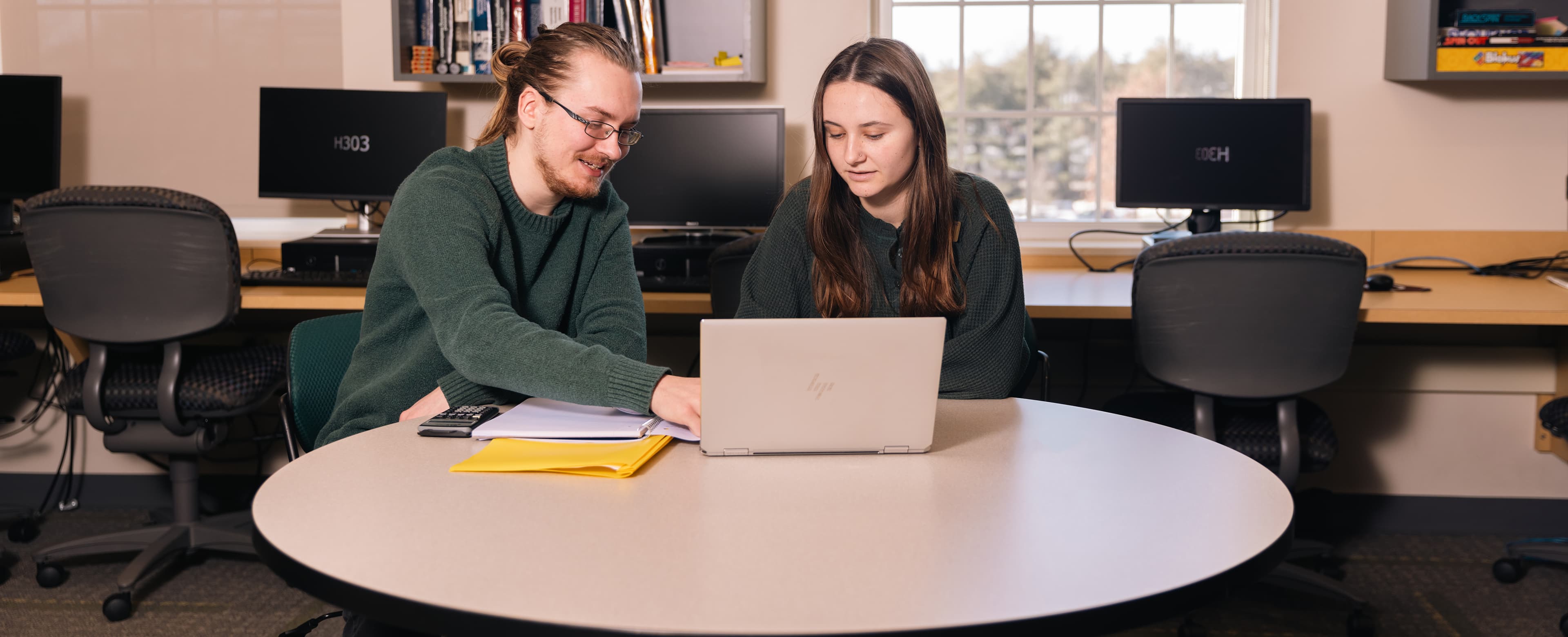 Two students working at laptop