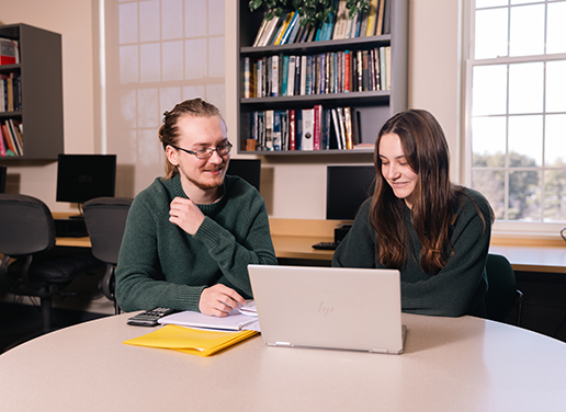 Two student working together at table with laptop