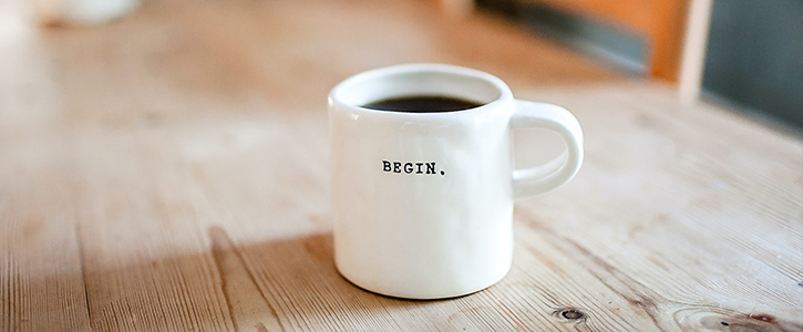 Coffee cup on a table stamped with "Begin"