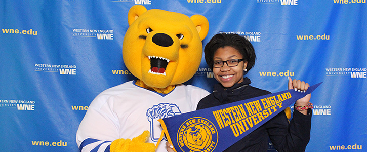 Student standing with "Spirit", the WNE mascot, holding WNE Banner
