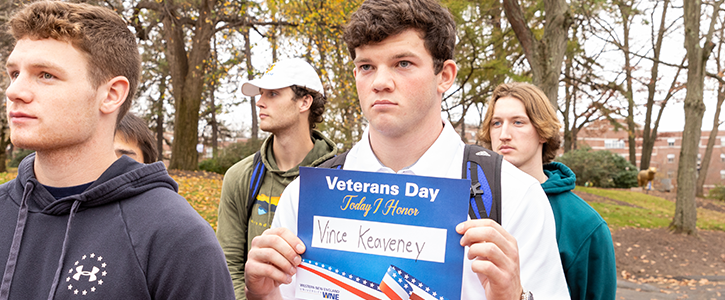 Attendee at Veteran's day event holding a sign in honor of a veteran