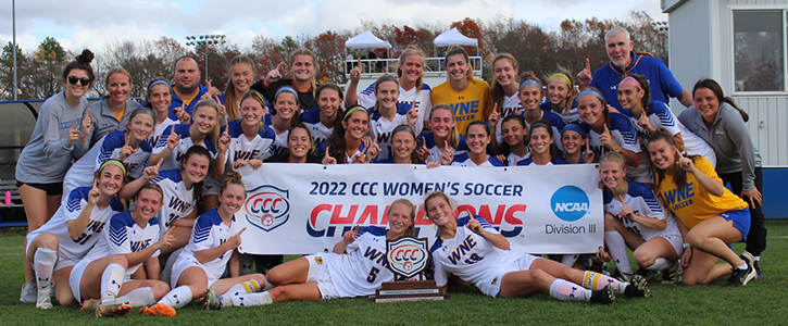 Women's soccer team in front of Championship banner