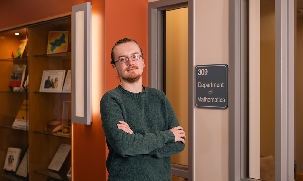 Daniel Podzunas (Mechanical Engineering, Math) standing at the door of the Department of Mathematics.