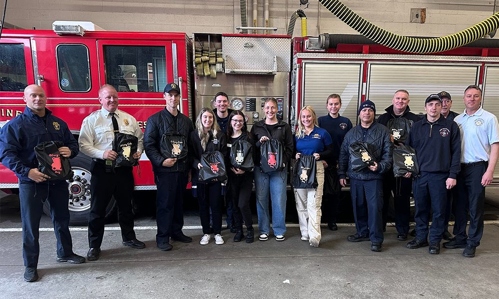 Members of the West Springfield Fire Department and WNE OTD students pose for a photo with BEary Bags in front of a fire engine at the WSFD station.