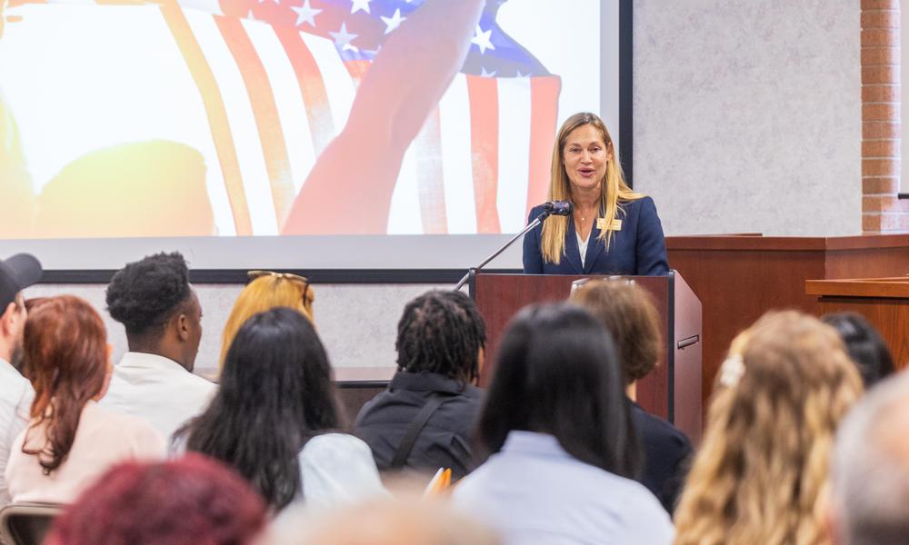 Professor at podium addresses court room 