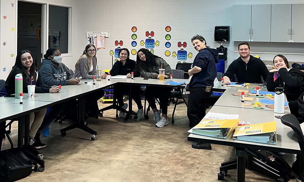 Occupational therapy students sitting around conference table doing exercises.