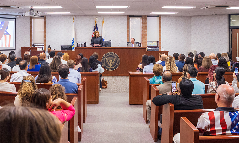 Broad photograph of the School of Law Moot Court with a federal judge presiding to deliver the Oath of Allegiance to 48 citizens.