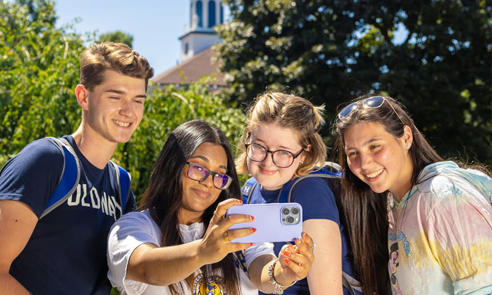 Potential students taking a selfie with a WNE student with the WNE cupola in the background.