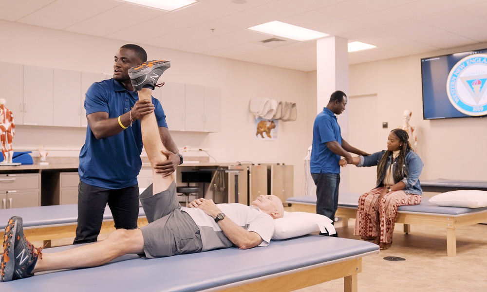 Occupational therapy student helps patient move leg during therapy.