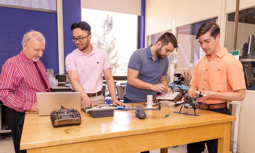 A professor shows electrical engineering students how to use circuits.