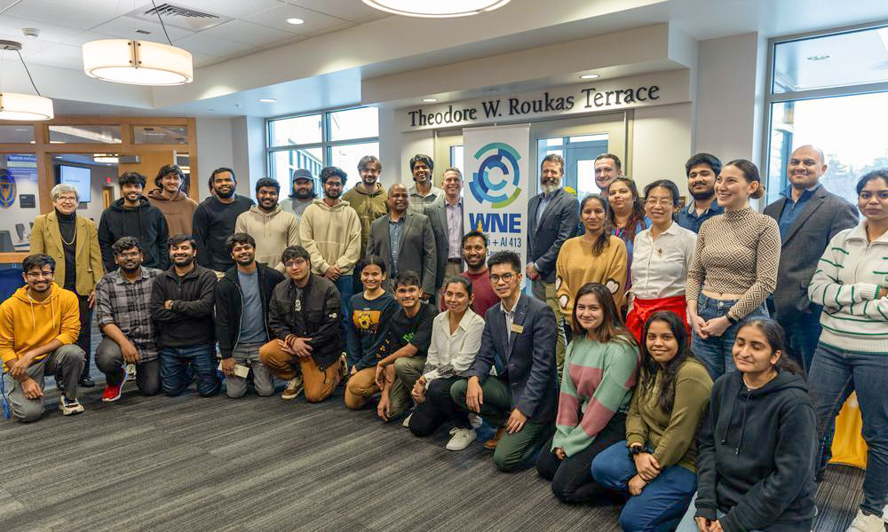 Approx. 35 students with faculty and team members from Country Bank and MassMutual stand in front of WNE banner.