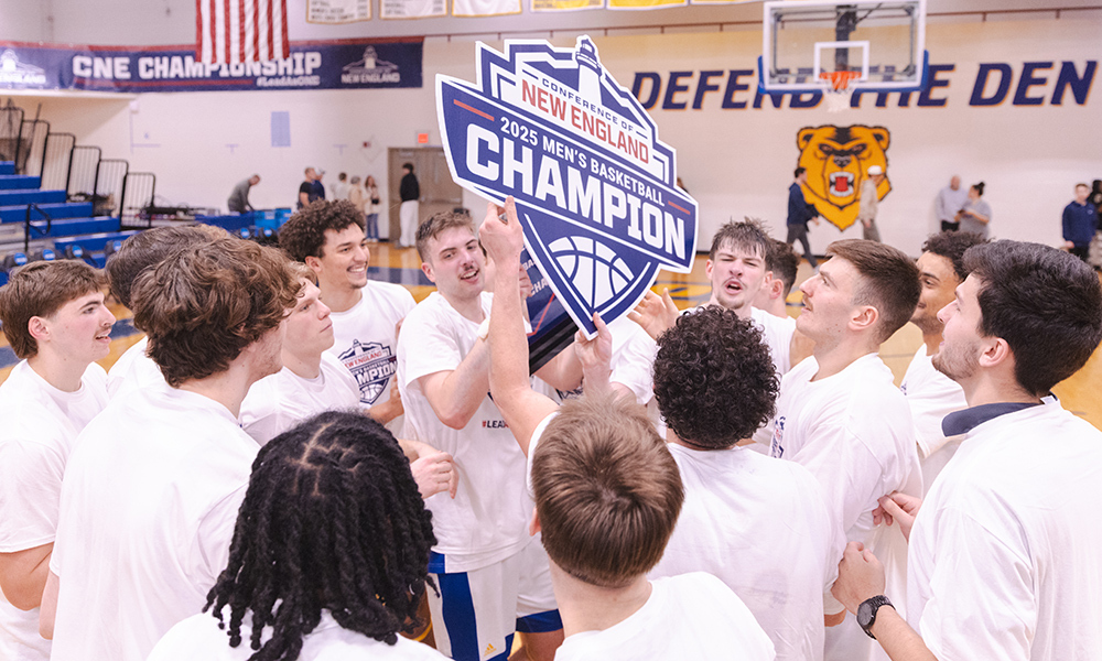 Men's basketball team in white jerseys holding sign in center of circle declaring them the division III winners