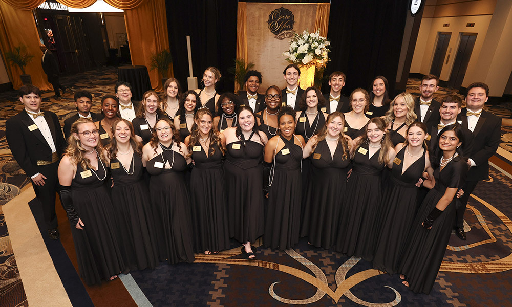 High shot of 29 WNE student ambassadors dressed in black tie and black gowns.
