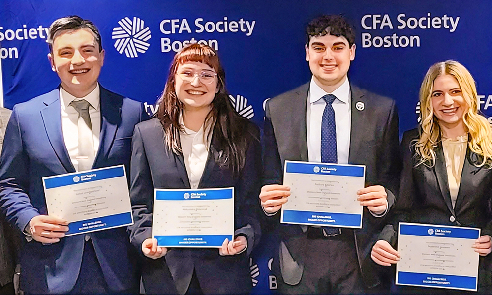Four students stand holding their winning CFA certificates.