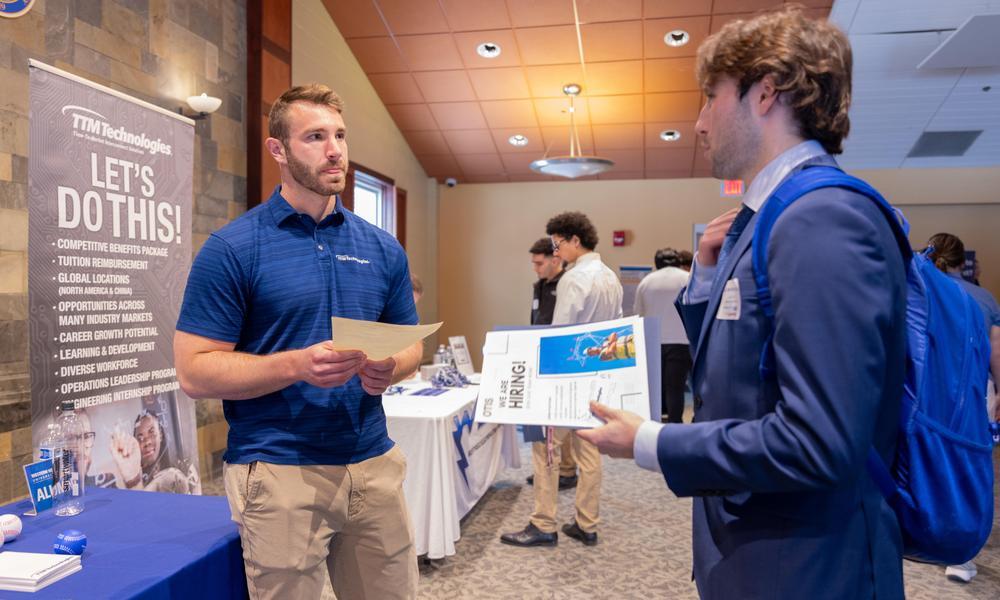 Student speaking to professional at a table during the 2026 spring career fair.